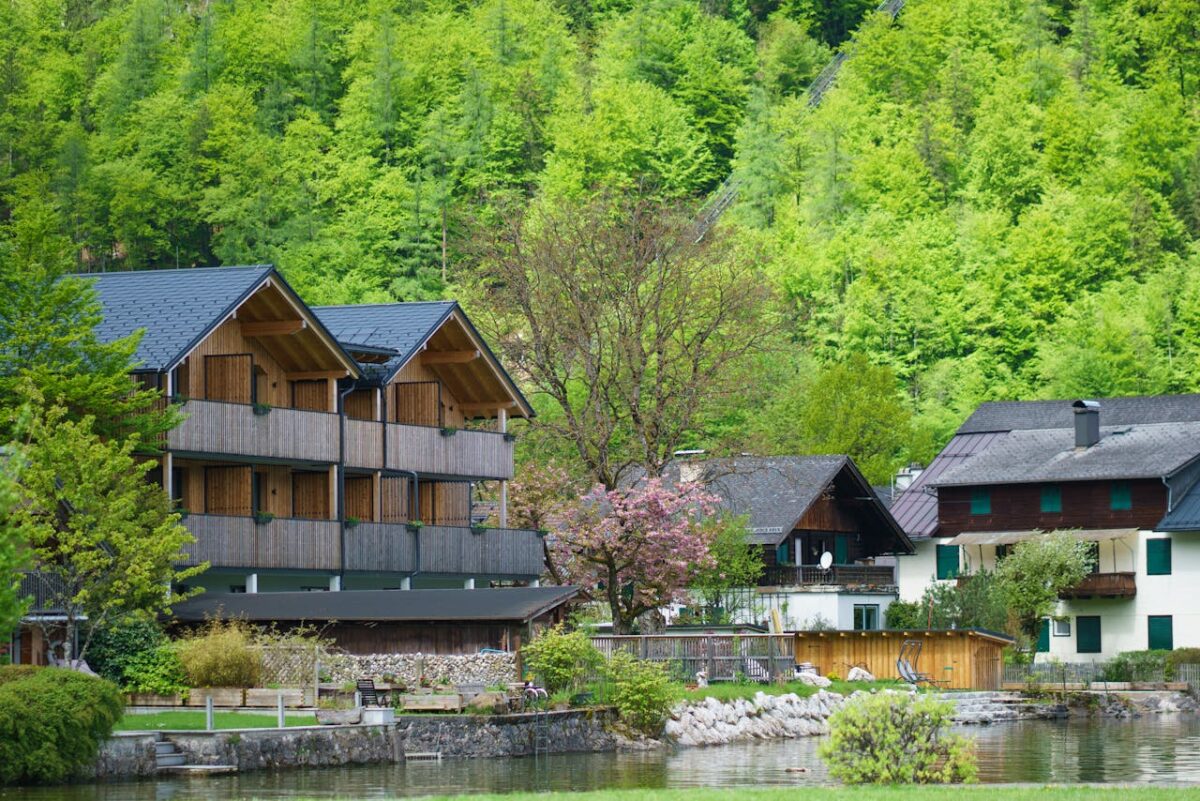 Charming village houses by a river, surrounded by vibrant spring greenery and blooming trees.