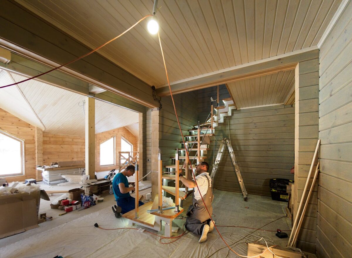 our-story-01 Carpenters skillfully assembling a modern wooden staircase inside a newly constructed home interior.